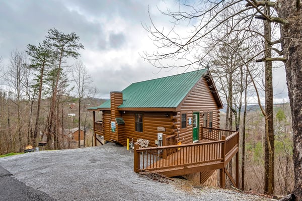 Two cabins side by side on a hillside with mountain views and autumn foliage in the background