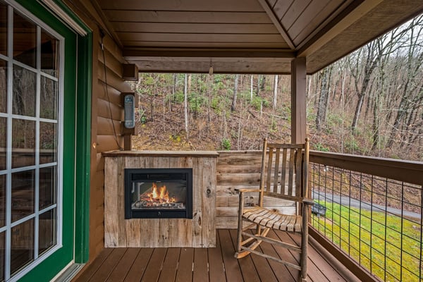 Covered wooden deck with metal railing overlooking forested property